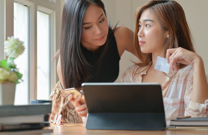 Two teenage girls are shopping online with a tablet at home to order and pay online by credit card.