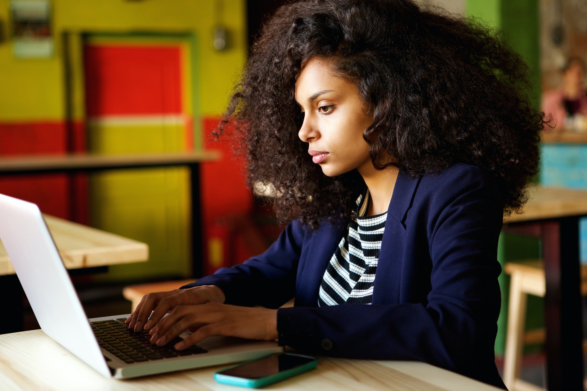 List of writing strategies: Woman writing on laptop at coffee shop