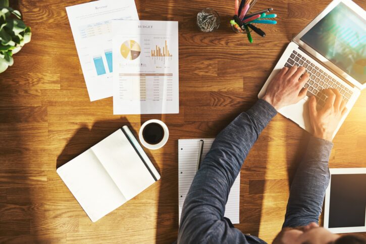 stories in sales funnel: person working on a laptop with open notebook, charts and graphs