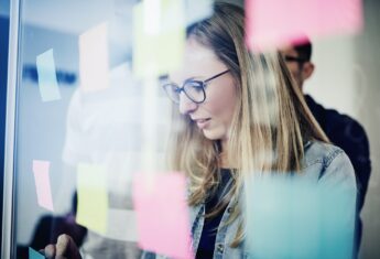 A businesswoman in front of a wall of sticky notes