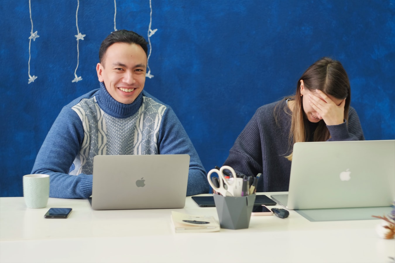 Smiling coworkers on their laptops.