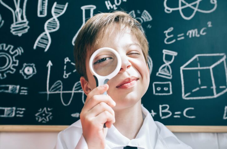 Little boy looking at camera through magnifying glass