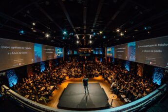 An image that shows a crowd gathered around a conference speaker.