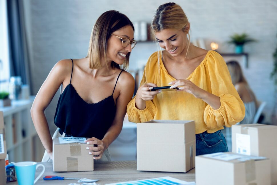 two beautiful freelance business women using smart phone to taking photos to sell online