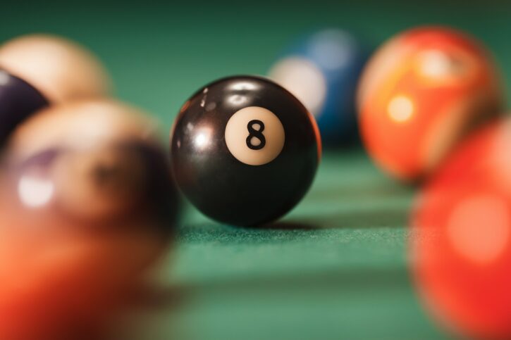 Pool ball with number 8 over green background.