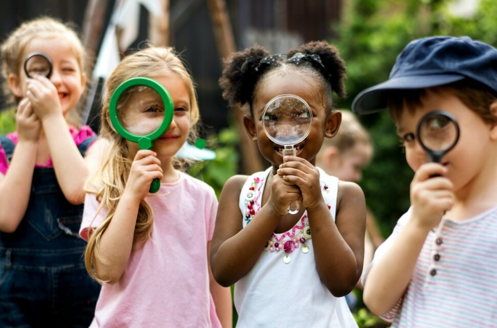 Group of kindergarten kids friends holding magnifying glass for explore